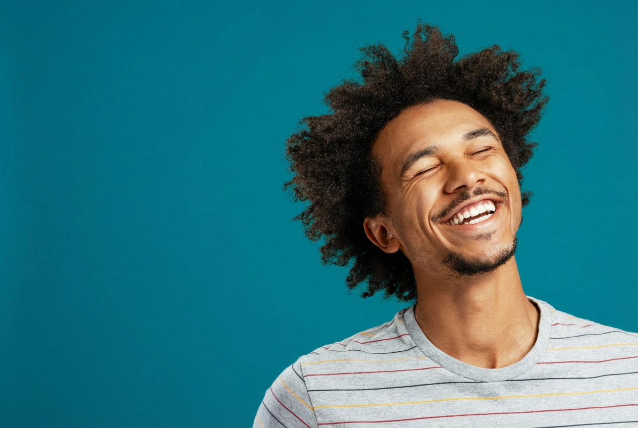 Smiling man with curly hair against a teal background